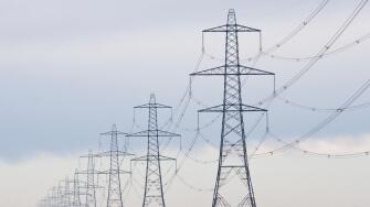 A long straight line of Electricity pylons receding into the distance on Walland Marshes, UK