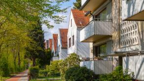 Modern german street with white stoned houses with tiled roofs. Sunny day and green alley.