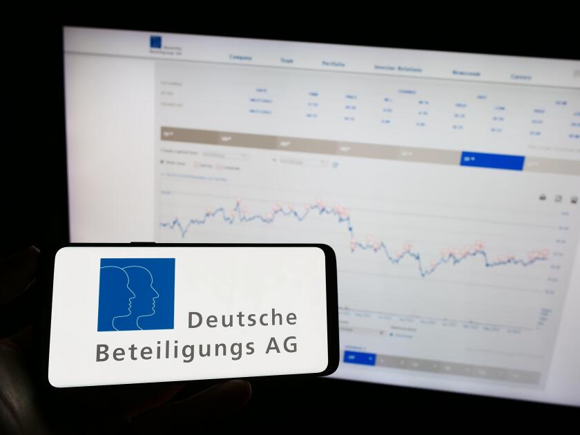 Person holding mobile phone with logo of German company Deutsche Beteiligungs AG (DBAG) on screen in front of web page. Focus on phone display.