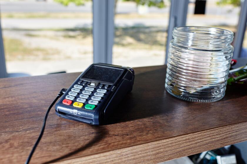 The credit card payment terminal is on the table in coffee shop cafe. Close-up of contactless payment device, card machine