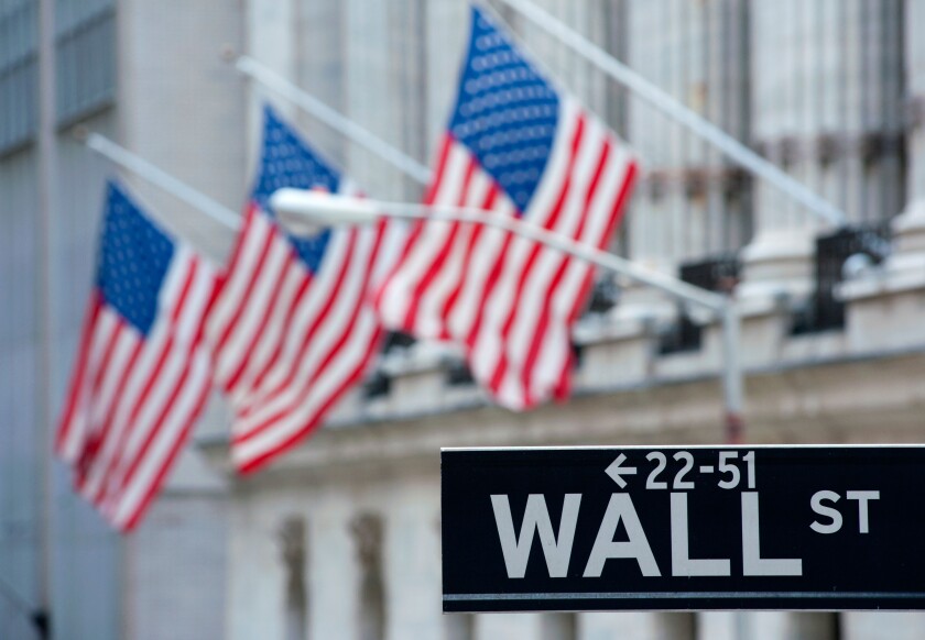 Detail of Wall Street sign with flags on Stock Exchange building to rear Manhattan New York City