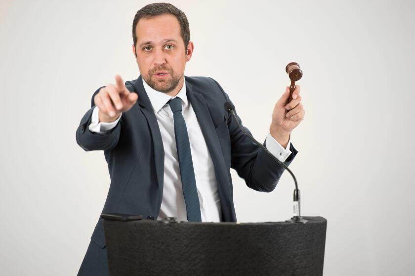 A male auctioneer in action holing a gavel during a live auction.