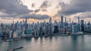 Aerial view of a vast cityscape with towering skyscrapers including the Empire State Building under a dramatic sky, New York, New York, United States.