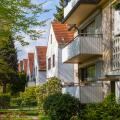 Modern german street with white stoned houses with tiled roofs. Sunny day and green alley.