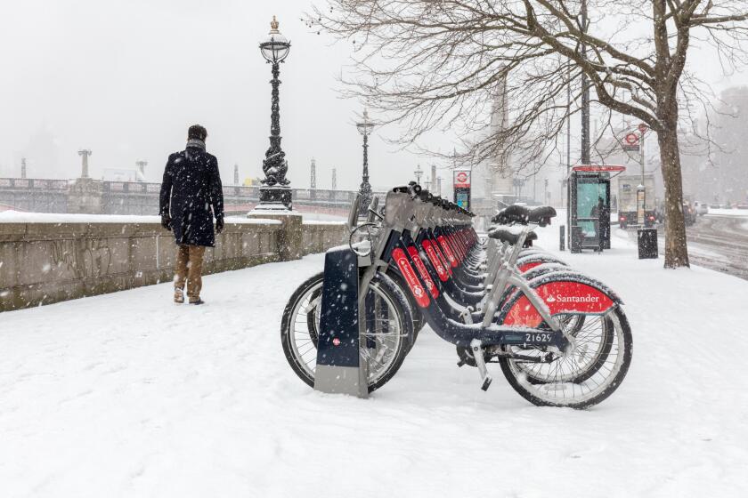 London, UK; 28th February 2018; Man walks past Line of Santander Bikes During Snowstorm