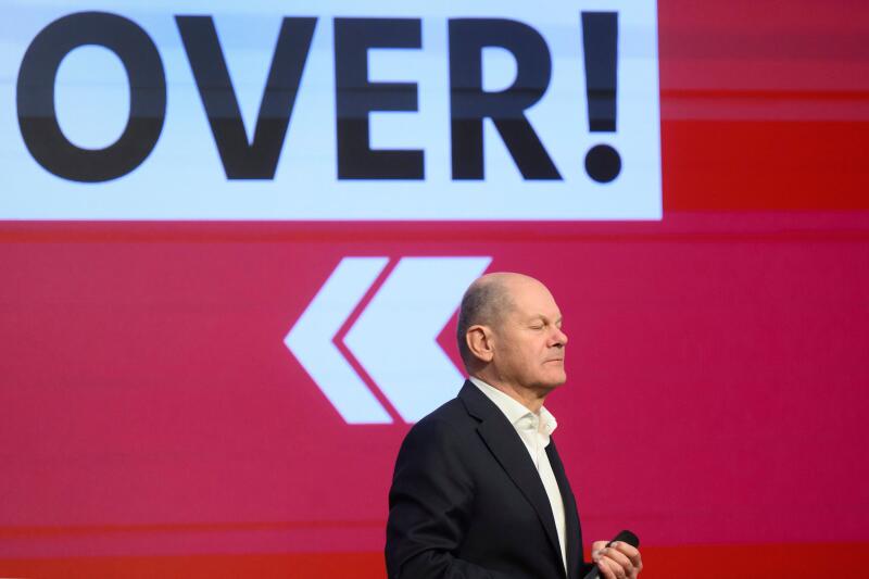 German Chancellor and member of the Olaf Scholz speaks in front of a sign reading 'OVER!' during a SPD Citizens' Dialogue at the Career Campus in Hannover, Germany, Thursday, Feb. 20, 2025. (Julian Stratenschulte/dpa via AP)
