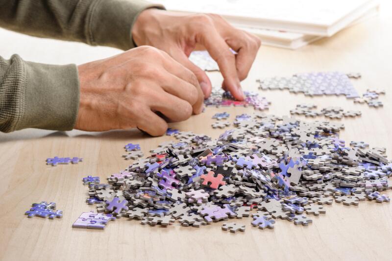 The man playing jigsaw puzzle game (focus at heap of jigsaw)