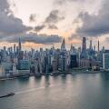 Aerial view of a vast cityscape with towering skyscrapers including the Empire State Building under a dramatic sky, New York, New York, United States.