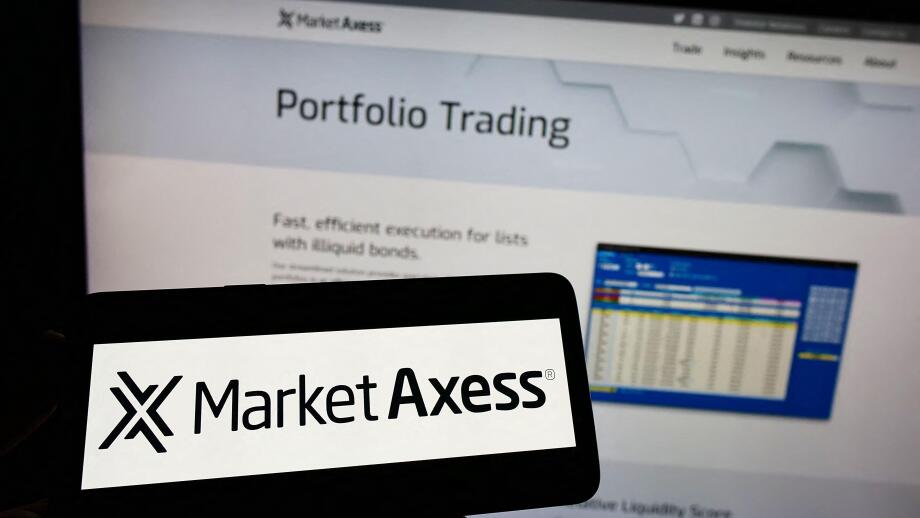 Person holding cellphone with logo of American financial company MarketAxess Holdings Inc. on screen in front of webpage. Focus on phone display.