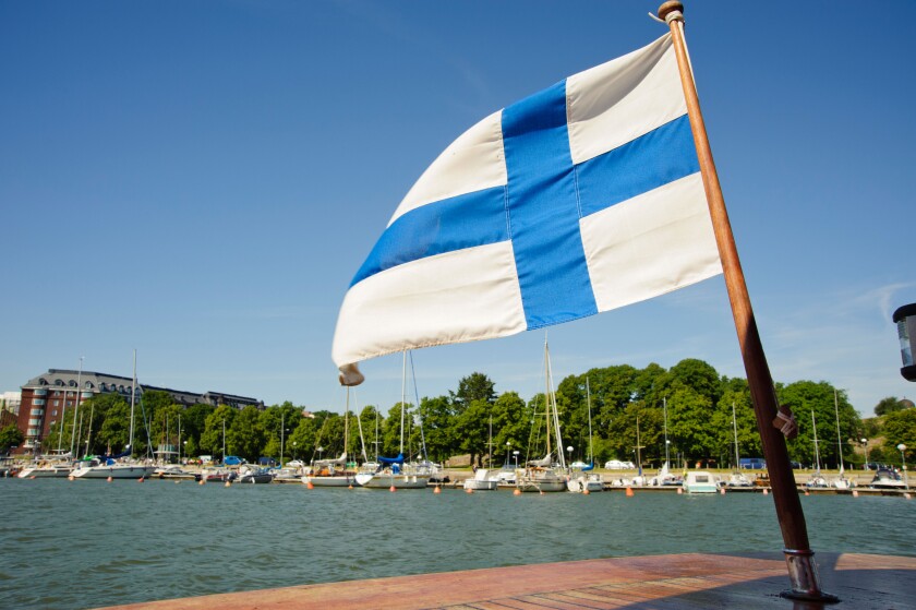 The Finnish flag flies from a boat shuttling between Unisaari island and the Merisatama quayside, Helsinki Finland