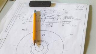Drawing and pencil lies on a metal table at the factory