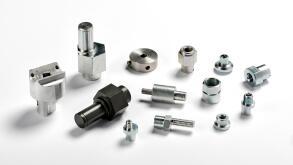 Assorted spare aluminium and iron parts and precision engineered components scattered on a white background with shadows