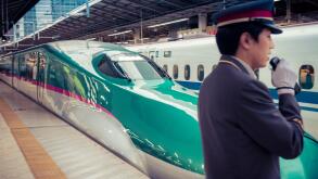 On Japan Railways both the trains and the service are polished. A shinkansen leaves Tokyo Station with a guard in the foreground.