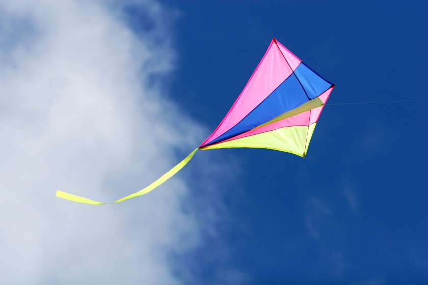 a kite flying against a blue sky in sunlight bright colors and streaming tail. Image shot 2007. Exact date unknown.