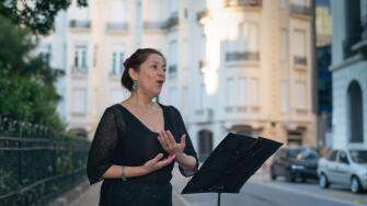 Soprano sings opera on an elegant street with a music stand