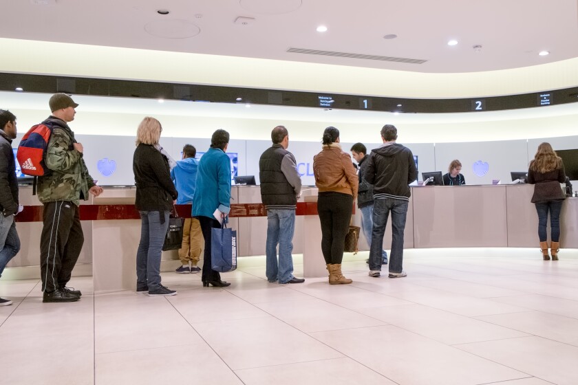 People queuing for counter service inside a high street branch of Barclay's bank UK