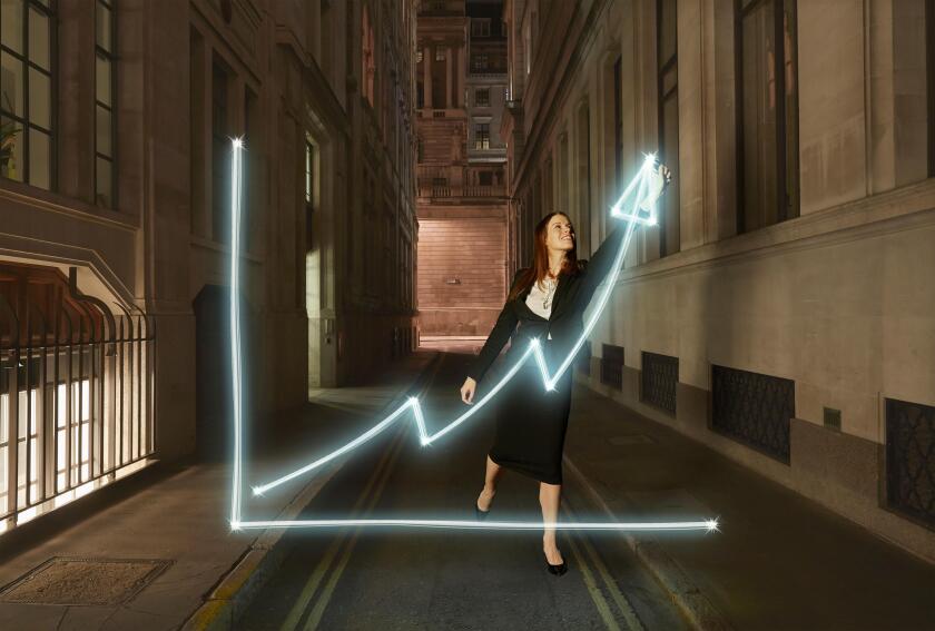 Businesswoman light painting glowing chart with upward arrow symbol  on city street at night