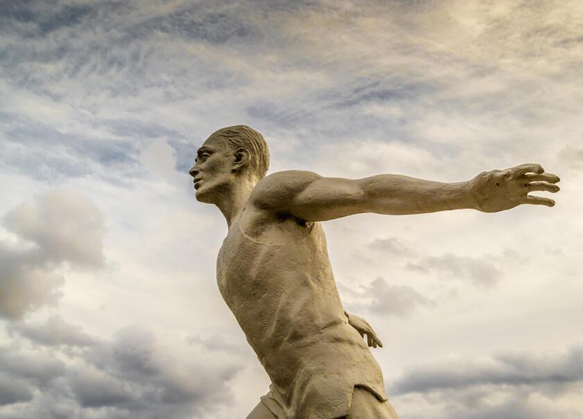 White stone statue of a man running in the clouds