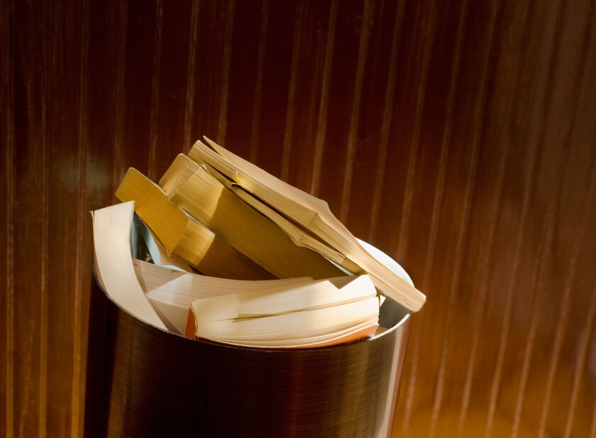 paperback books piled in trash can