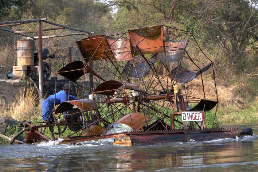 Worker operating a floating waterwheel on the Lower Zambezi River Zambia Zimbabwe Africa