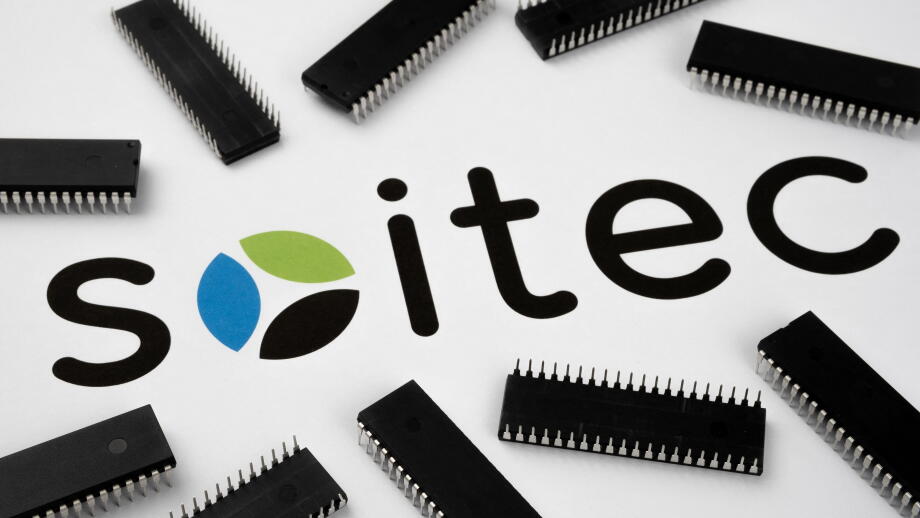 SOITEC company logo on the paper document and large microchips placed around. Illustrative for electronic chip manufacturer.  Selective focus. Staffor