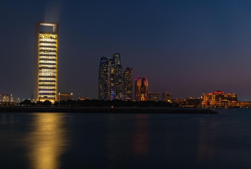 A picture of the Etihad Towers, the Abu Dhabi National Oil Company Headquarters and the Emirates Palace Mandarin Oriental Hotel at night.