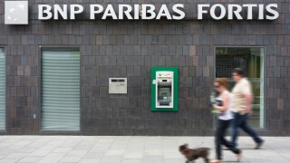 Couple walking past ATM cash dispenser at cashpoint of the BNP Paribas Fortis bank