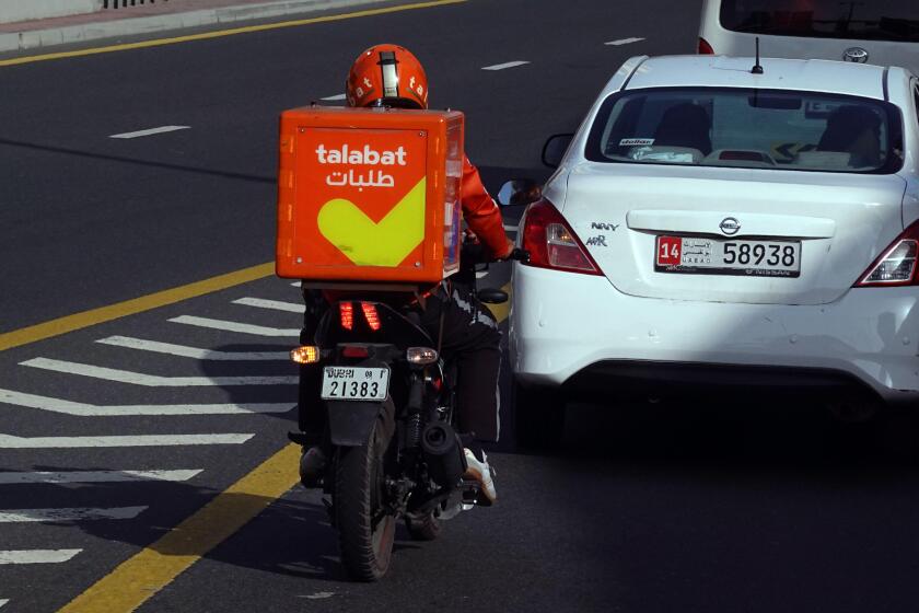 22.03.2022, Dubai, , United Arab Emirates - Employee of food delivery service talabat riding a motorcycle in the city. 00S220322D902CAROEX.JPG [MODEL