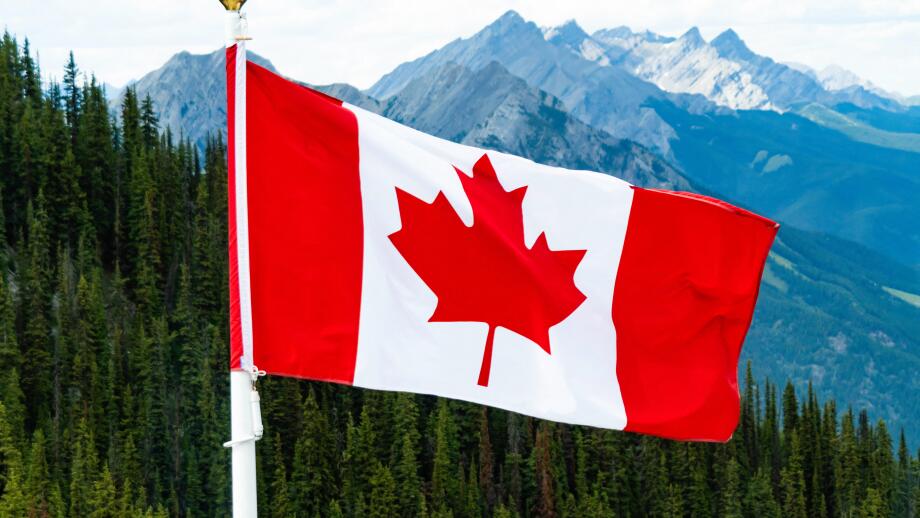 Canadian Maple Leaf national Flag flying over mountains