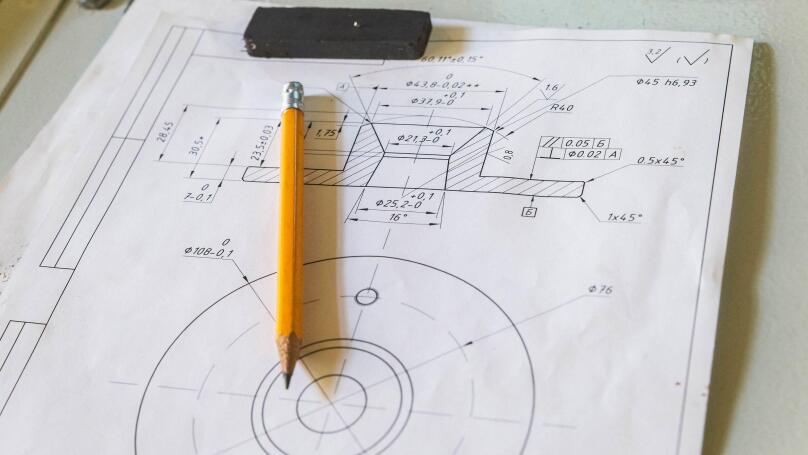 Drawing and pencil lies on a metal table at the factory