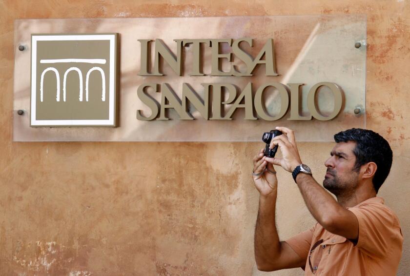 A man takes a picture in front of Intesa Sanpaolo bank in downtown Rome July 23, 2010. The European Union is examining whether some banks need to raise capital as it looks to dispel concerns about weakness in the sector and repair an interbank lending mar