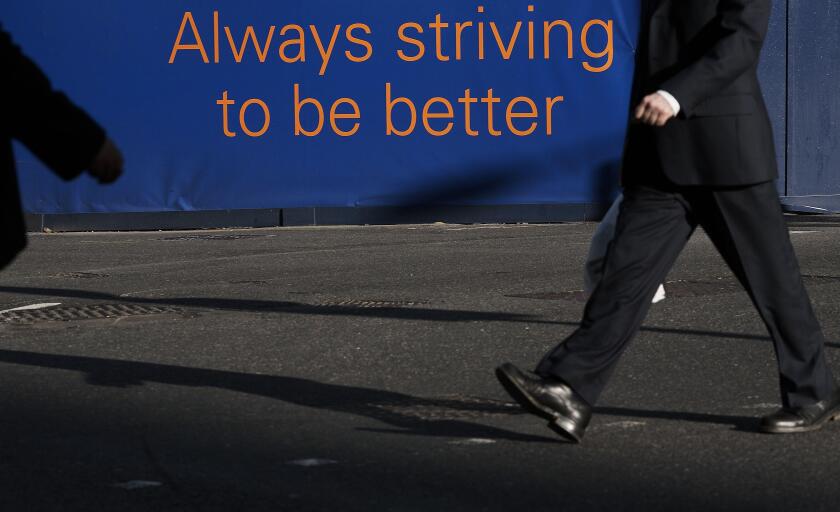GREAT BRITAIN / England /Canary Wharf/ Banker in Canary Wharf with sign Always striving to be better.