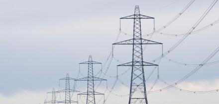 A long straight line of Electricity pylons receding into the distance on Walland Marshes, UK