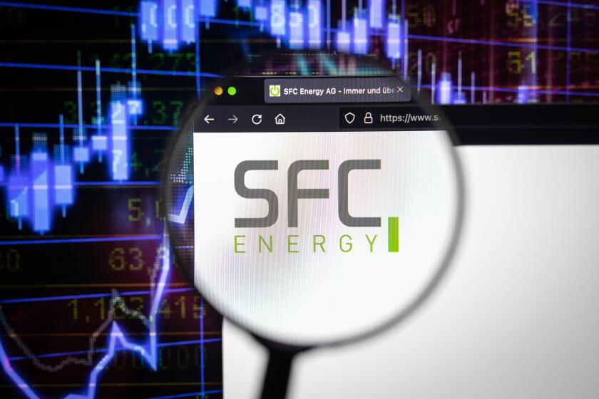 SFC Energy company logo on a website with blurry stock market developments in the background, seen on a computer screen through a magnifying glass