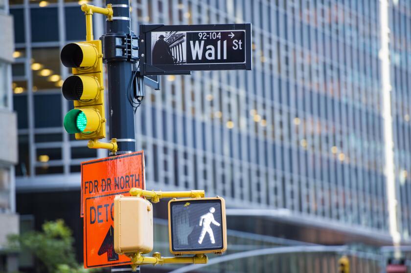 Wall street sign in the foreground and a huge blurred building in the background in Manhattan.