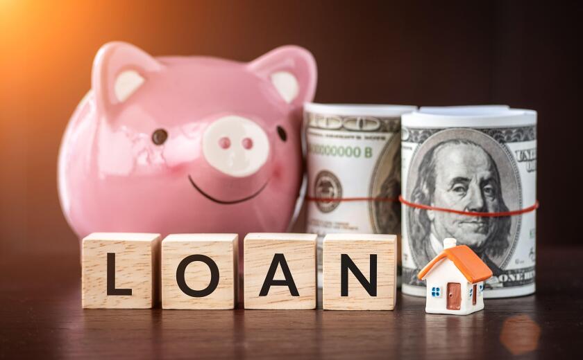 Real estate sale, savings, home loans market concept. model house with text loan on wooden cube, smilely pink Piggy bank and bank note