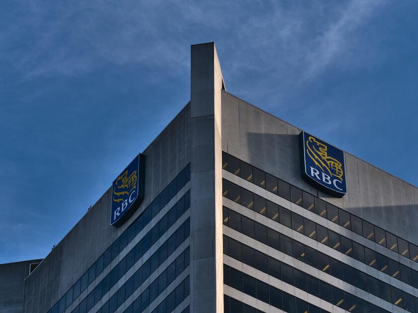 Low angle view of tall skyscraper with offices in Vancouver downtown with logo of Royal Bank of Canada (RBC) on top and blue sky.