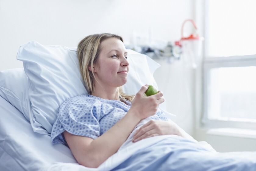 Patient lying in hospital bed eating apple