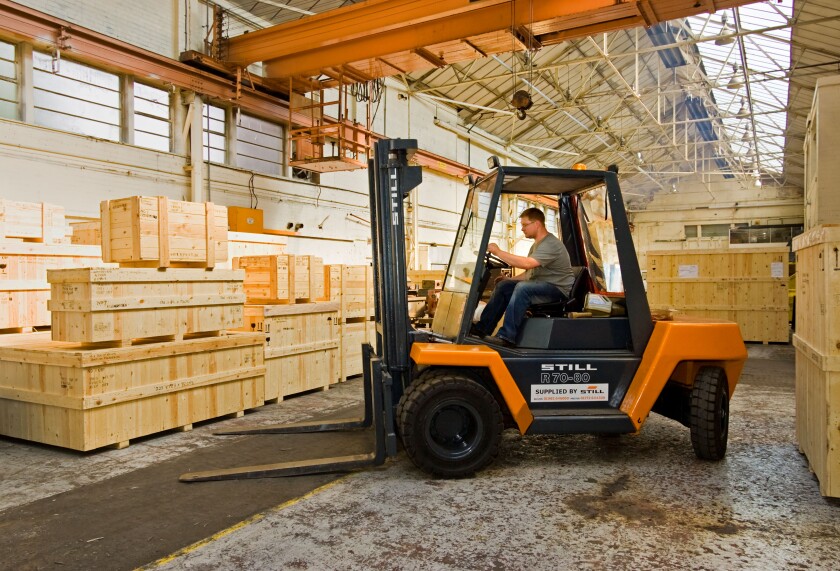 Warehouse - Man driving forklift truck, UK