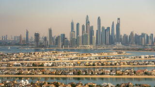 Aerial view of the luxury villas of the Palm Island and of the skyline of Dubai Marina, UAE. Hazy sky, pollution from the city. Futuristic skyline