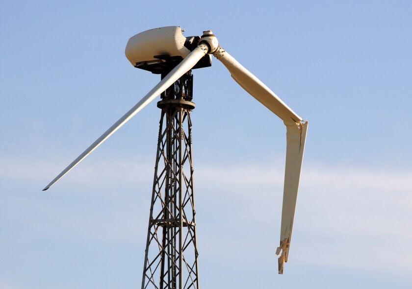 one broken wing on a single wind turbine against a blue sky