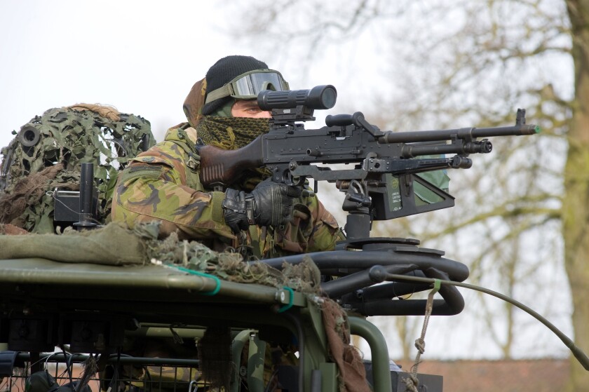 A soldier of the dutch army is aiming his automatic weapon during a training in the winter