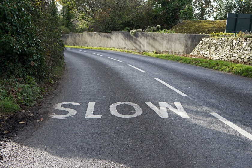 a slow sign painted in the road near a bend, uk