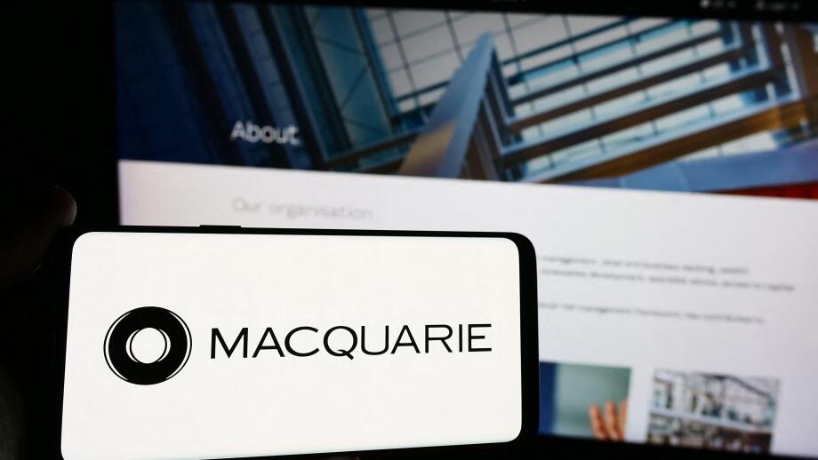 Person holding smartphone with logo of Australian financial company Macquarie Group Limited in front of website. Focus on phone display.