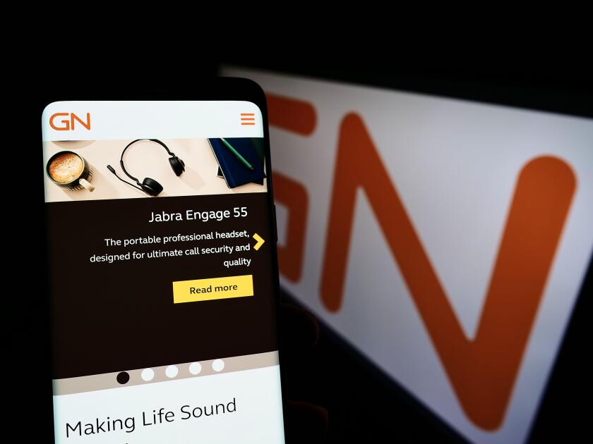 Person holding smartphone with website of Danish electronics company GN Store Nord AS on screen with logo. Focus on center of phone display.