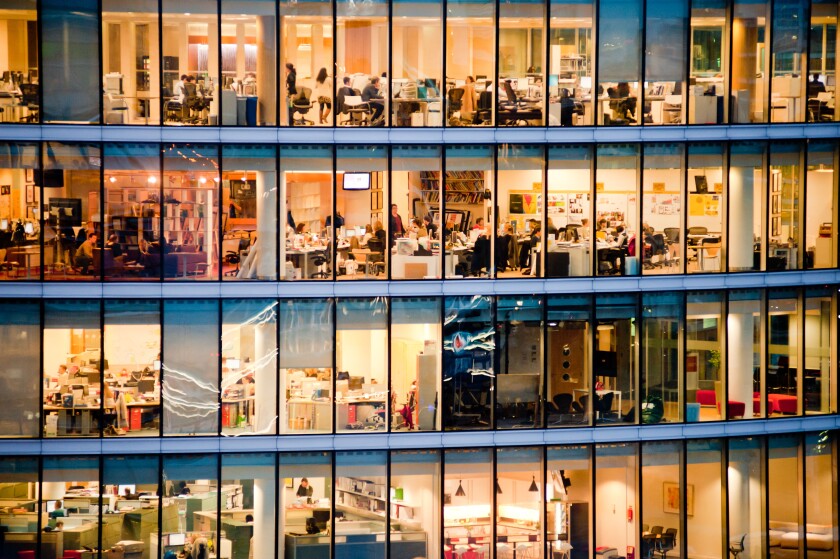 London, UK - February 2013: people work in a modern office building at dusk.