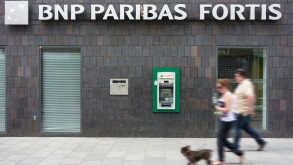 Couple walking past ATM cash dispenser at cashpoint of the BNP Paribas Fortis bank