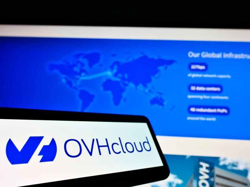 Mobile phone with logo of French cloud computing provider OVH Groupe SAS on screen in front of website. Focus on center-left of phone display.