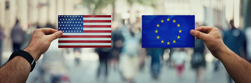 Two hands holding different flags, EU vs USA on politics arena over crowded street background. Future strategy, relations between countries. Cooperati