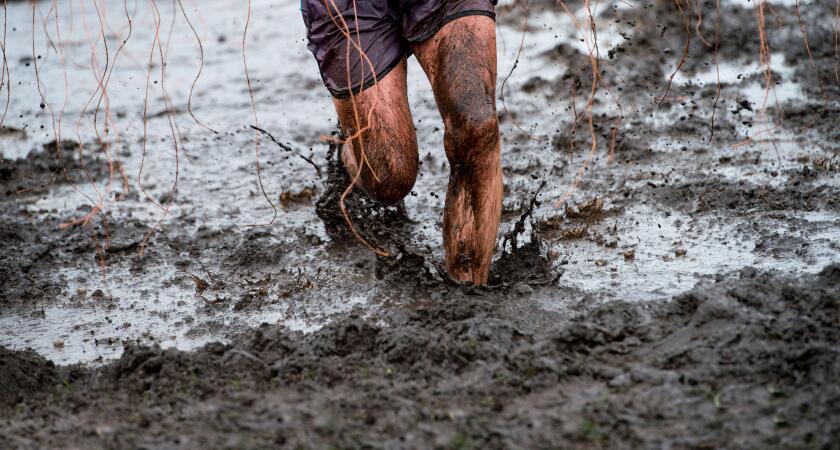 Mud race runner, man running in mud. Runners during extreme obstacle races. Active life and sport concept
